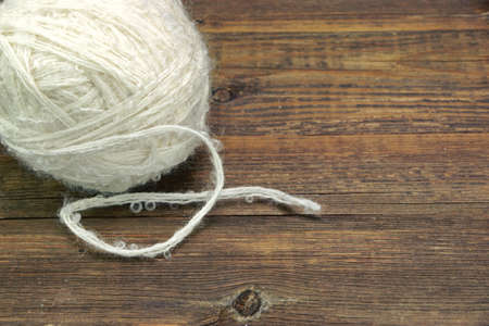 Natural Textured White Single Sheep Wool Roll or Ball or Tangle Closeup On Rustic Wood Table or Board or Floor  Backgroundの写真素材