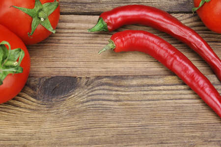 Two Fresh Red Hot Chili Peppers And Three Tomatoes On The Rustic Wood Kitchen Table. Background With Copy Space. Ingredients for Soup, Salad, Pasteの写真素材