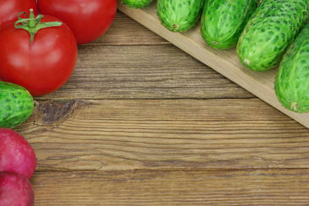 Vegetable Salad Ingredients On The Wood Cutting Board. Tomatoes, Cucumbers, Radish On The Kitchen Tabletopの写真素材