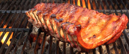 BBQ Baby Back Spicy Marinated And Smoked Pork Ribs On The Hot Charcoal Grill With Bright Flames On...
