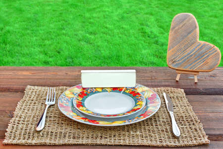 Picnic Table With Tableware, Wooden Heart And White Blank Signboard, Spring Lawn In The Background
