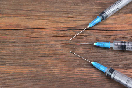 Three Empty Medical Syringes On Rough Wood Board Backgroundの写真素材