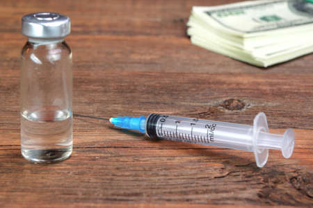 Money Wad, Syringe And Vial On Rough Wood Table.の写真素材