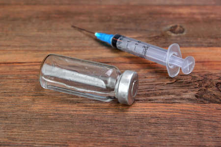 Single Small  Syringe And Vial On Rough Wood Board Backgroundの写真素材