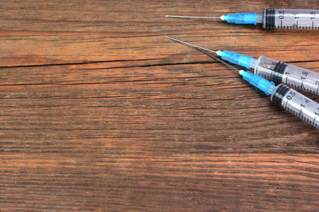 Three Empty Medical Syringes On Rough Wood Board Backgroundの写真素材