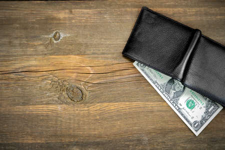 Open Male Black Leather Wallet With USA One Dollar Bill On Old Rough Brown Wood Background With Copy Spaceの写真素材