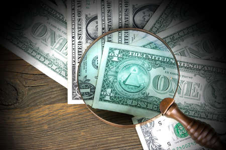 One Dollar Bills Under Vintage Magnifier Glass On The Rough Old Wood Backgroundの写真素材