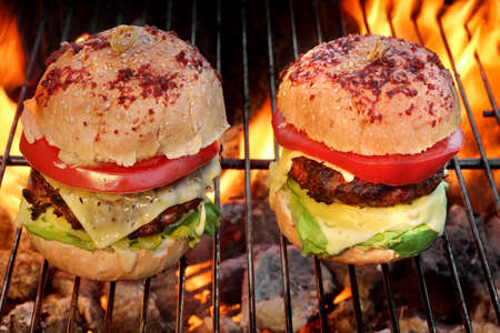 Close-up Of Two Homemade Cheeseburgers On The Flaming BBQ Grill On The Backgroundの写真素材