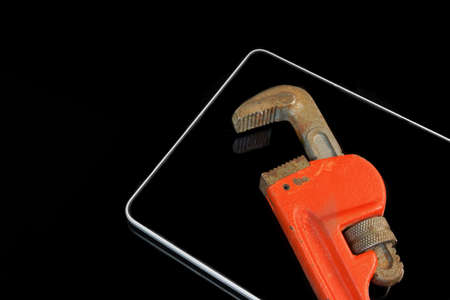 Tablet Computer And Adjustable Wrench Isolated On Black  Isolated On Black Glass  Background With Reflection. High Angle Viewの写真素材
