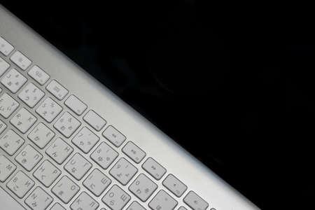 High Angle View Close-up Of Multilingual  Wireless Keyboard Isolated On Black Background With Copy Space. English, Chinese And Russian Letters Ans Symbolsの写真素材