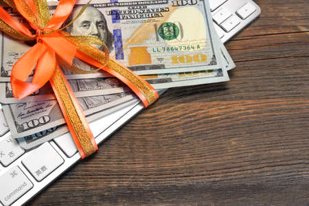 Money Tied With A Ribbon On The Computer Keyboard On The Rough Wood Backgroundの写真素材