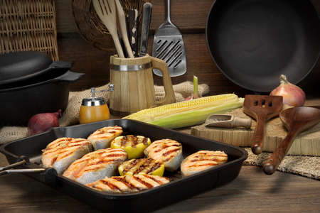 Still Life  In The  Rustic Style With Grilled Salmon Steaks On The Rough Wooden Tabletop With Different Kitchen Utensilsの写真素材