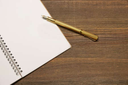 Opened Spiral Bound Notebook With Blank White Pages, Real Gold luxury Fountain Pen  On The Rustic Rough Brown Wooden Tableの写真素材