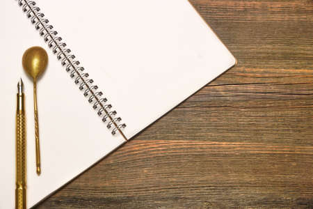 Opened Spiral Bound Notebook With Blank White Pages, Vintage Old Spoon And Gold Fountain Pen  On The Rustic Rough Brown Wooden Tableの写真素材