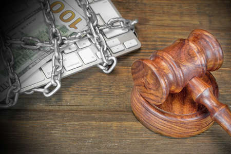 Cyber Crime Concept, Judges Gavel And Keyboard Is Wrapped By Chain On The Rough Brown Wood Table