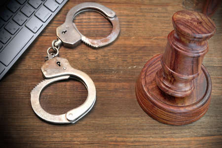 Cyber Crime Concept, Judges Gavel Computer Keyboard  And Real Handcuffs On The Rough Brown Wood Tableの写真素材