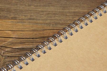 Closed Spiral Bound Notebook With Brown Paper Cover On Wood Rough Rustic Table Background Texture, Top Viewの写真素材