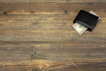High Angle View Of Modern Black leather Men's Wallet With Dollar Cash On The Old Rough Wood Textured Background With Copy Spaceの写真素材