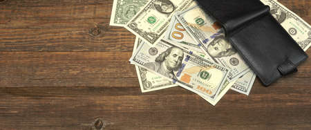 High Angle View Of Modern Black leather Men's Wallet With Dollar Cash On The Old Rough Wood Textured Background With Copy Spaceの写真素材