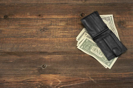 High Angle View Of Modern Black leather Men's Wallet With Dollar Cash On The Old Rough Wood Textured Background With Copy Spaceの写真素材