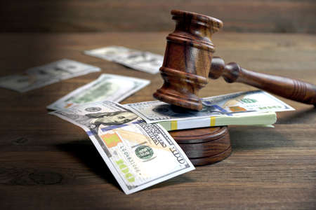 Concept For Corruption, Bankruptcy Court, Bail, Crime, Bribing, Fraud, Auction Bidding. Judges or Auctioneer Gavel, Soundboard And Bundle Of Dollar Cash On The Rough Wooden Textured Table Background.の写真素材