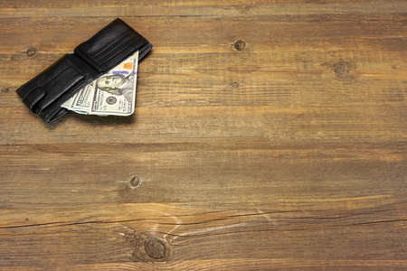 High Angle View Of Modern Black leather Men's Wallet With Dollar Cash On The Old Rough Wood Textured...