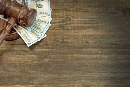 Concept For Corruption, Bankruptcy Court, Bail, Crime, Bribing, Fraud, Auction Bidding. Judges or Auctioneer Gavel, Soundboard And Bundle Of Dollar Cash On The Rough Wooden Textured Table Background.の写真素材