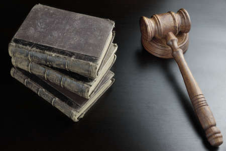 Judges  Or Auctioneers Walnut Gavel And Old Law Book  On The Black Wooden Table Background In The Back Light. Overhead View. Lawsuit or Auction Bidding Conceptの写真素材