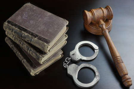 Judges Gavel, Handcuffs And Old Law Book  On The Black Wooden Table Background In The Back Light....