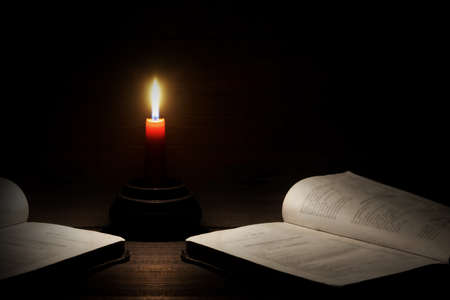 Lighted Candle And Two Open Books On The Rough Wood Horizontal Background With Copy Space