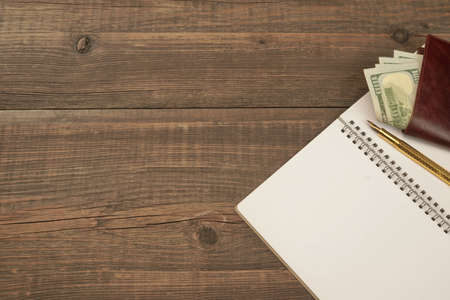 Opened Spiral Notepad With Blank White Page, Golden Fountain Pen And Purse With Dollar Cash On The...