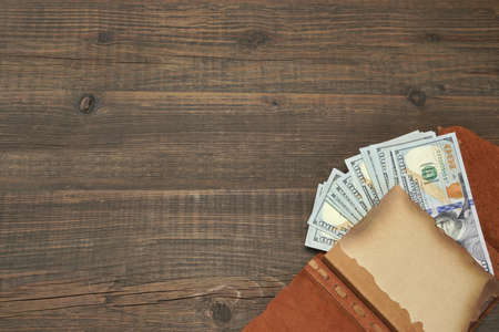 Notepad With American Dollar Cash On The Rough Rustic  Brown Wood Baclground With Copy Space, Conceptual Image For Home Or Own Financeの写真素材