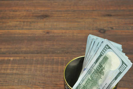 American One Hundred Dollar Bills In The  Tin Can Top View On The Rough Wooden Table Background With Copy Spaceの写真素材