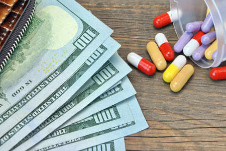 Wallet With US Dollar Cash And Scattered Pills On The Rough Wood Background, Top View, Conceptual...