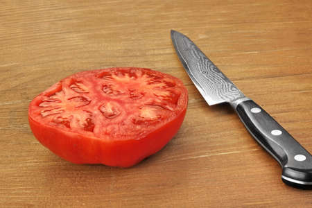 Ripe Sliced Red Large Tomato And Japanese Kitchen Knife On Wood Table Background, Closeup, Top View