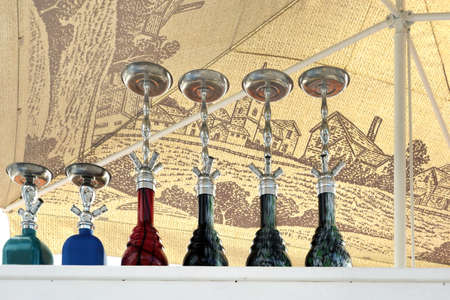Group Of Modern Ceramic And Glass Hookah Or Shisha Appliance On The White Wooden Bar Counter, Sea...