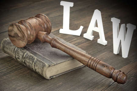 Judges Gavel Or Hammer, Silver Metal Handcuffs and Old Vintage Law Book On Wooden Table In The...