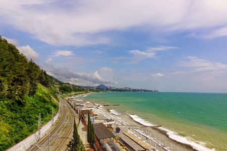 Russian Railway Track Running Along The Black Sea Shore Beach. Horizontal Summer Landscape. The view from Dagomys Village In The Direction To Sochi City. Internal Travel Concept.の写真素材