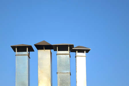 Four Galvanized Chimney Pipe Or Vent Pipe In A Row On Blue Sky Backgroundの写真素材