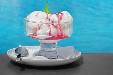 Misted Glass Vase With Ice Cream Sundae Balls And Fruit Syrup On The Black Metal Table At The...