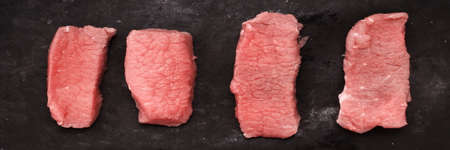 Raw Beef or Veal Slices Cuts. Beef Steaks on Wooden Black Board. Flank Beef Steaks On Grungy Black...