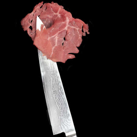 Carpaccio Slice and Japanese Damascus Stainless Steel Chef Knife Isolated On Black Background, Front View. Marbled Beef Carpaccio On Sharp Kitchen Knife.の写真素材