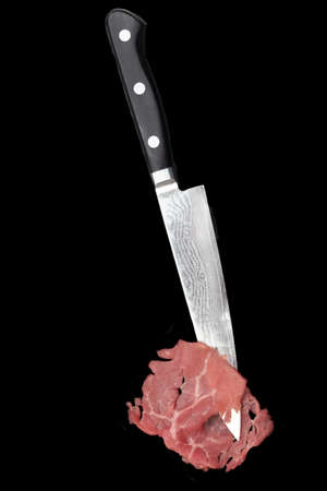 Carpaccio Slice and Japanese Damascus Stainless Steel Chef Knife Isolated On Black Background, Front View. Marbled Beef Carpaccio On Sharp Kitchen Knife.の写真素材