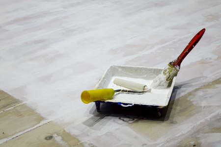 Paintbrush, Paint Brush, Paint Roller, Paint Tray With White Paint On Wooden Floor Background. Room Wooden Flooring Repair Work. Room Floor Renovation.の写真素材