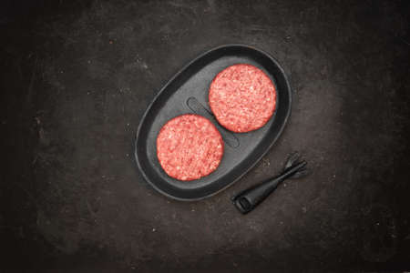 Raw Minced Homemade Grill Beef Burgers in Frying Pan, Top View. Griddle Grill Pap and Ground Beef Meat Patties for Grilling on Black Background, Overhead View. Raw Steak Burgers Cutlets On Grill Pan.の写真素材