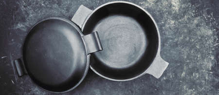 Cast Iron Pot With Cover Or Lid In The Form Of Separate Frying Pan. Top View. Casserole Pot On Black Shabby Background. Flat Lay. New And Clean Cast Iron Cookware.の写真素材