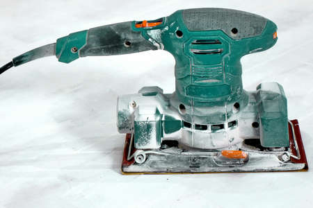 Electrical Sanding Machine On The Paint Wooden White Floor With Sandpaper