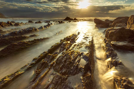 Strong sun Reflected in the sea and rocksの写真素材