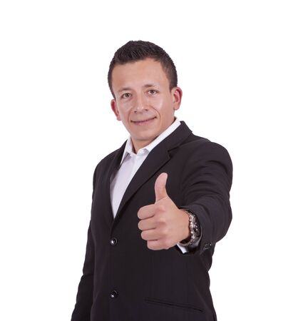 Portrait of a smiling young businessman gesturing thumbs up while standing against whiteの写真素材
