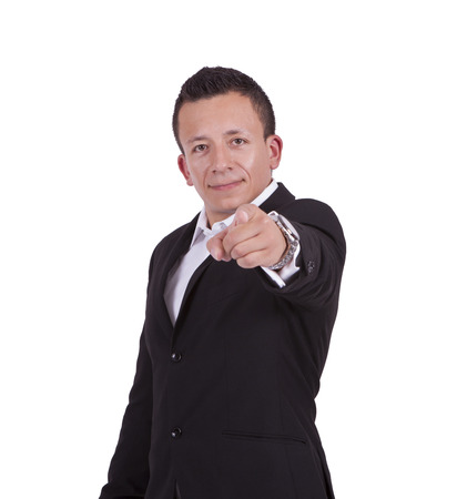 Portrait of a young businessman pointing towards camera while standing against whiteの写真素材